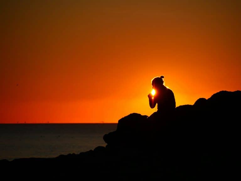 Woman meditating in the morning sunlight as part of daily rituals for inner peace.