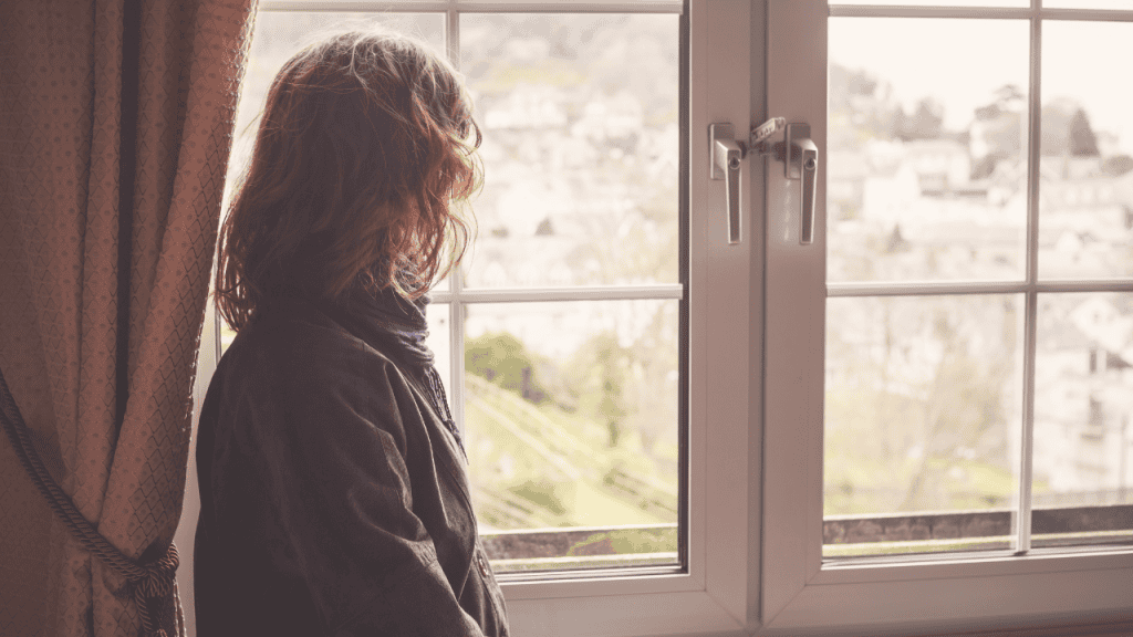 person feeling lost in life sitting alone by the window reflecting
